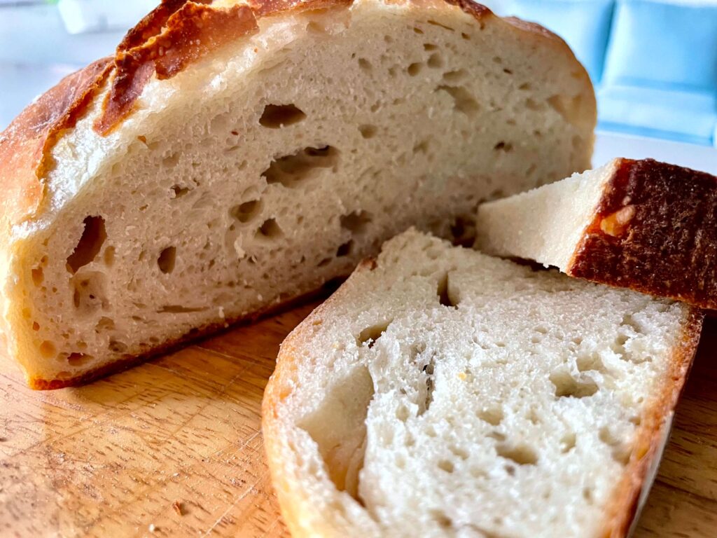 Easy Dutch oven bread sliced in half with two pieces sitting in front 