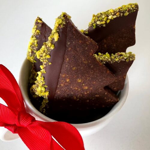 Chocolate pistachio Christmas tree cookies in a cup with a festive red bow