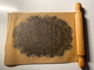 Chocolate pistachio shortbread dough that has been rolled out between two pieces of baking paper