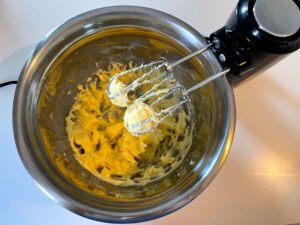 Creamed butter and icing sugar in a stainless-steel bowl with a hand mixer