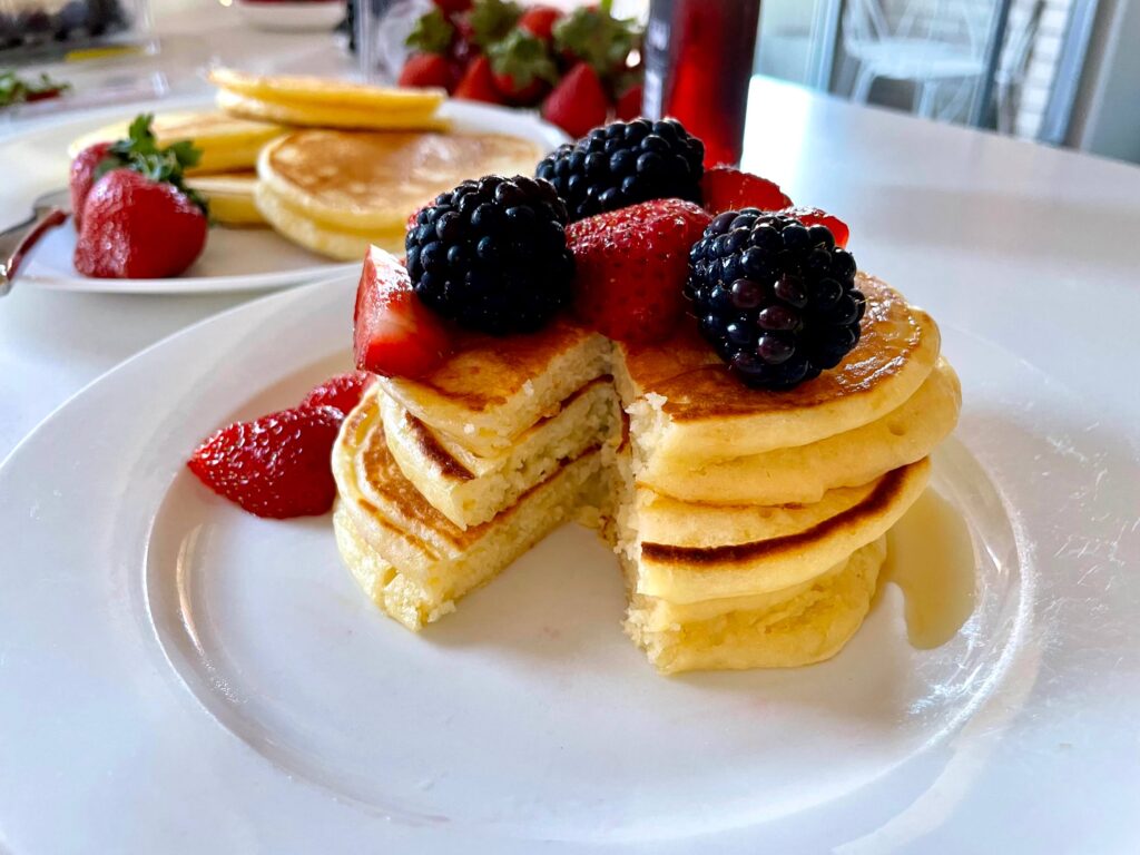 A stack of buttermilk pancakes with strawberries and blackberries on top