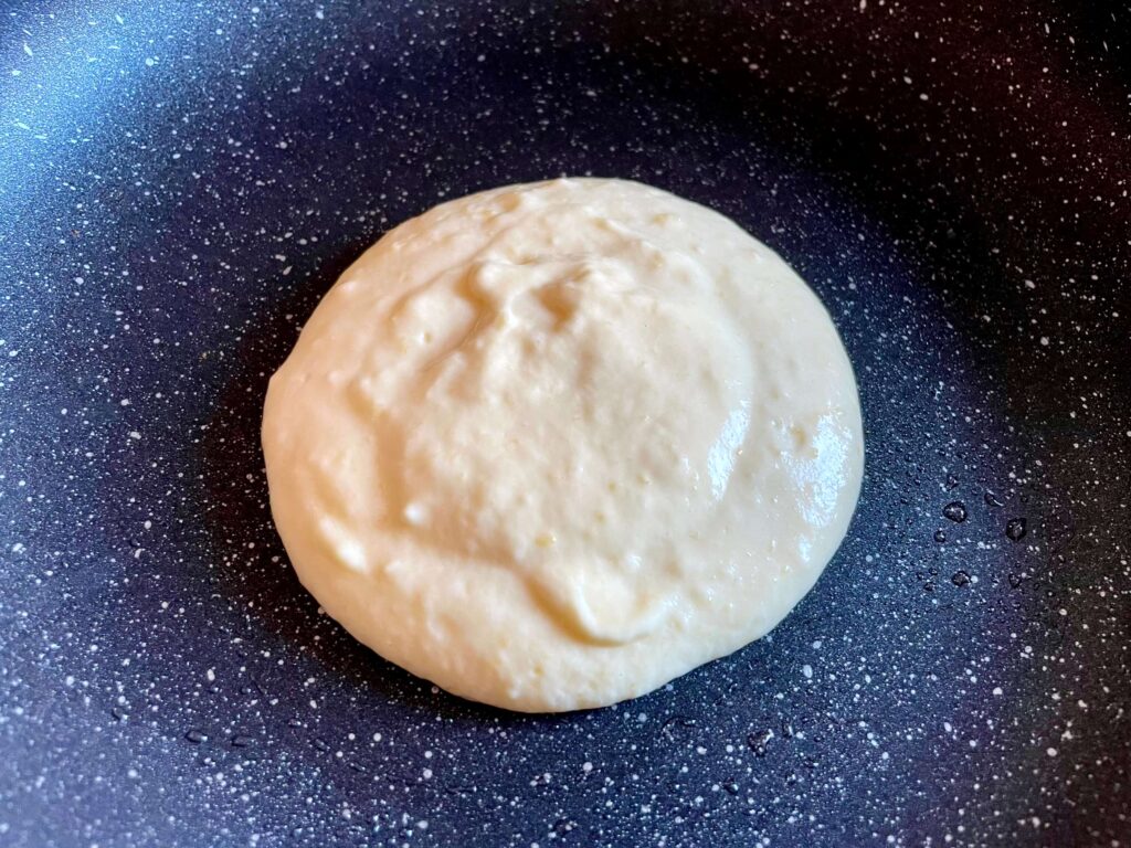 Pancake batter poured into the hot greased frying pan in a circle shape
